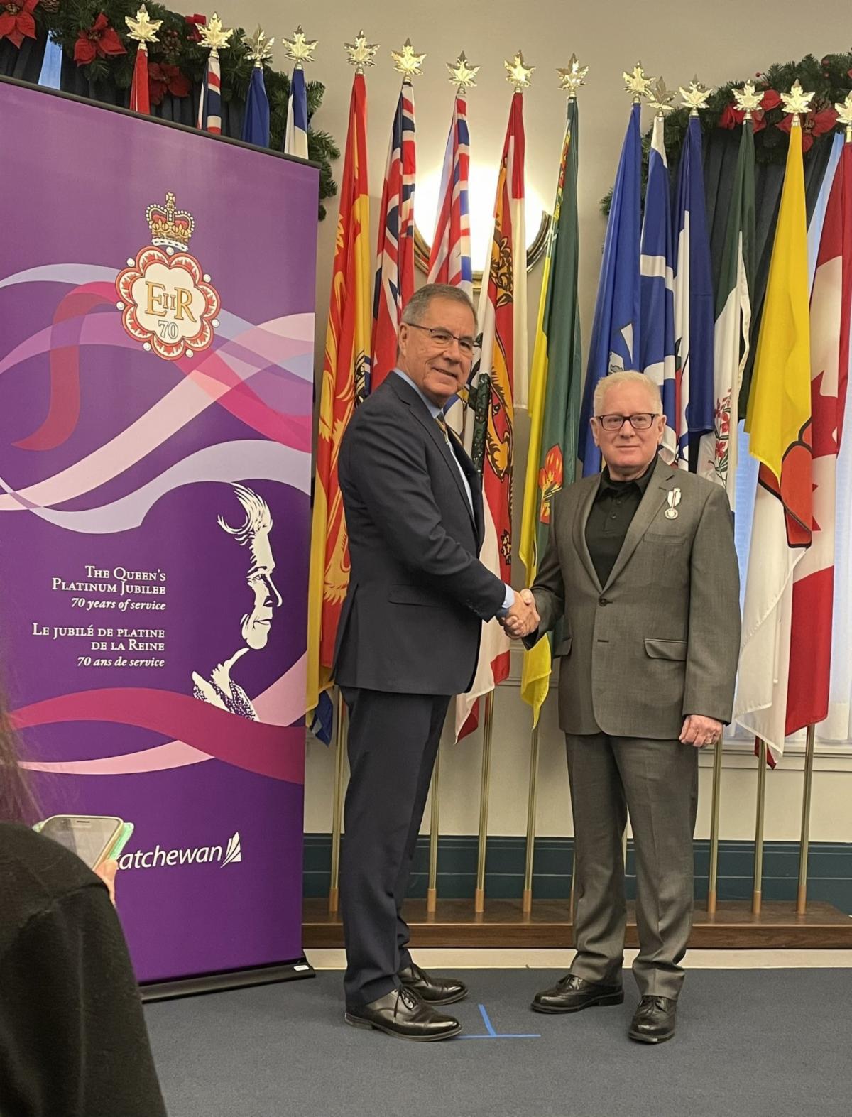 Don Larson shakes hands and poses while receiving a Queen Elizabeth II Platinum Jubilee Medal