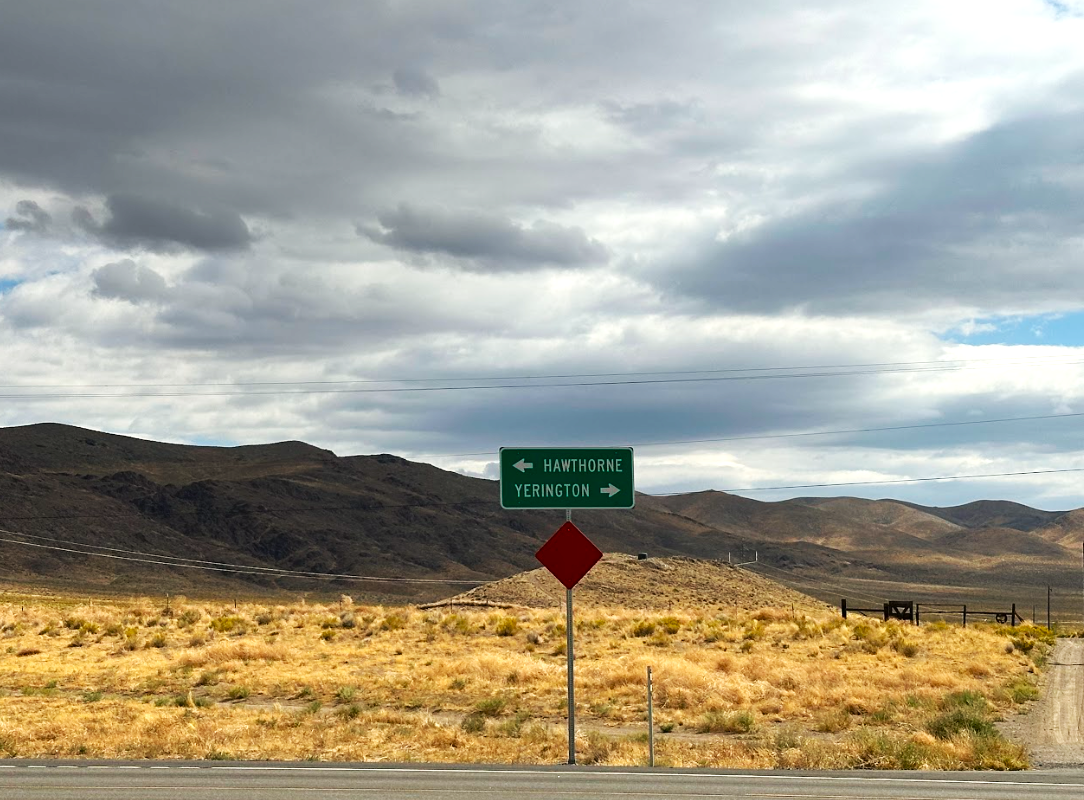 a road sign in the desert with mountains in the background