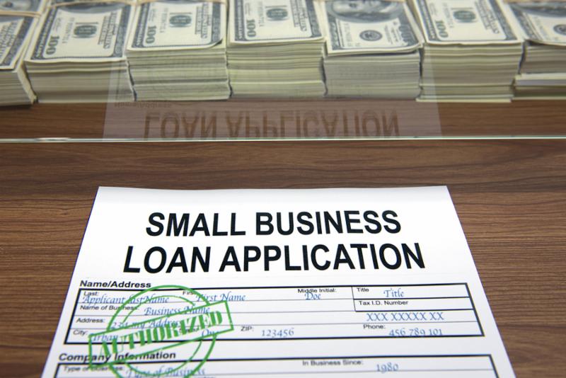 Approved small business loan application and dollar bills