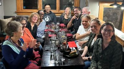 diverse group of adults smiling while seated tightly around a table