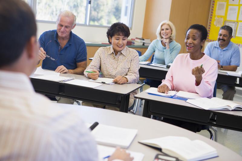 Adult students in class with teacher  selective focus 