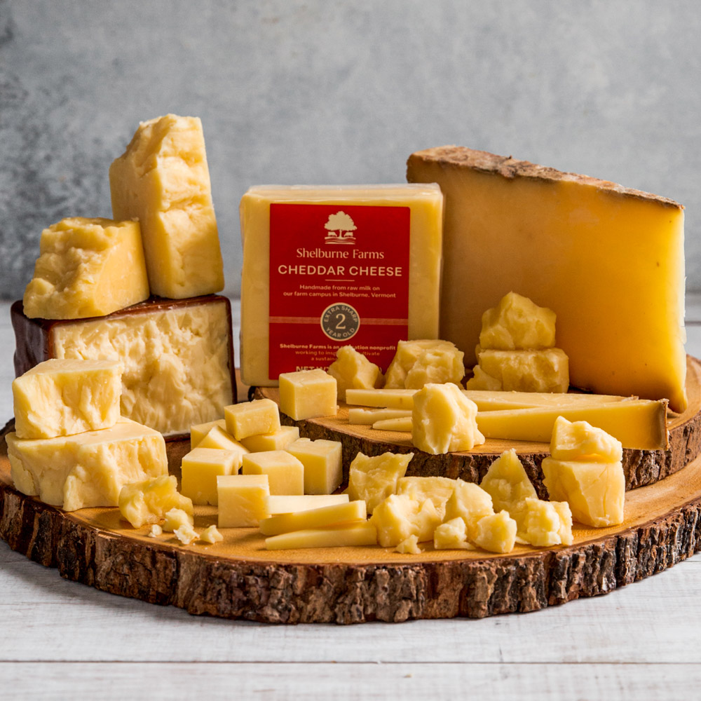 A wooden serving board with piles of cheddar cheese