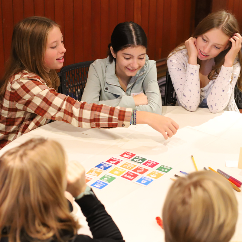 Students sit at a table laying out colorful cards during an activity