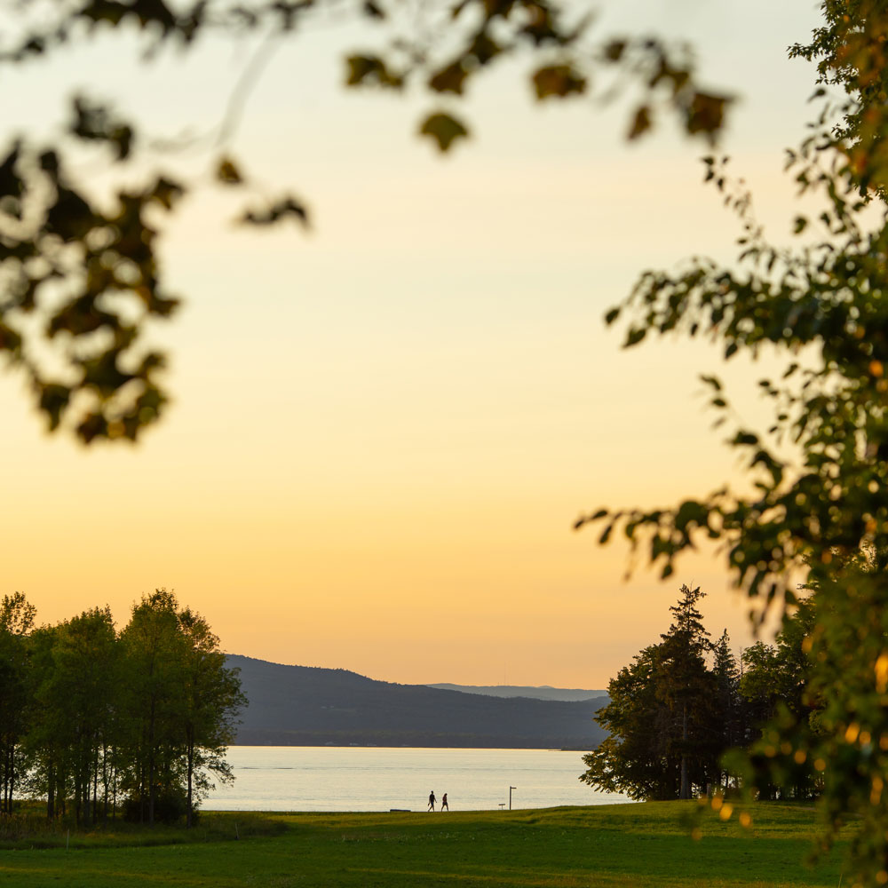 A lake scene during sunset, two figures walking in the distance