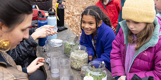 Young children make tea in an outdoor kitchen