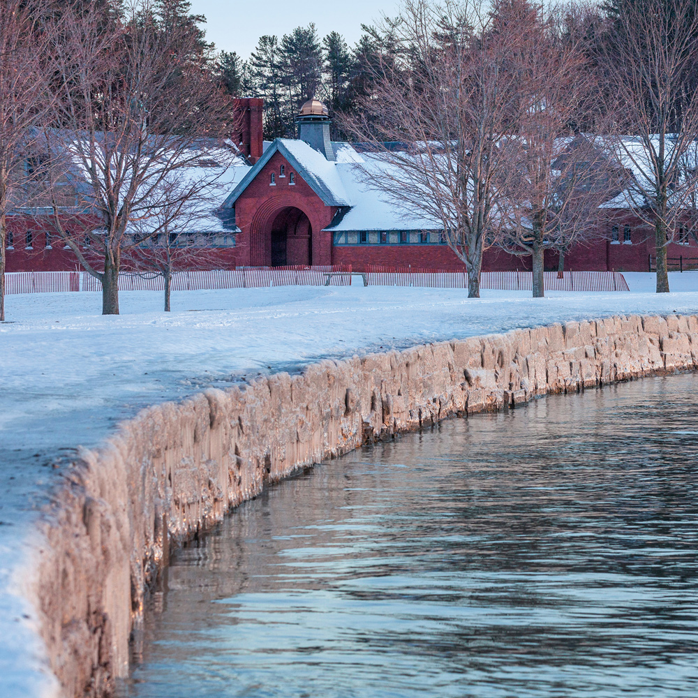 The Coach Barn in the distance, a snowy field and Lake Champlain in the foreground