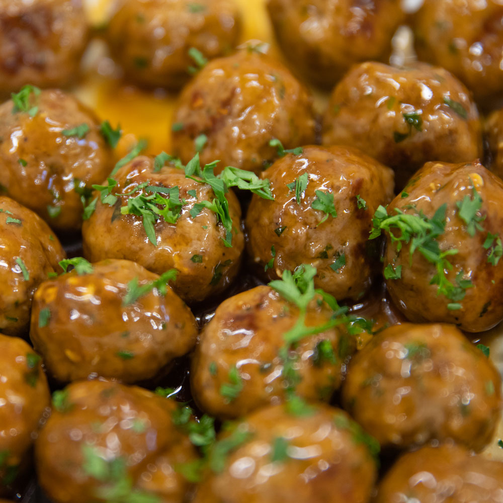 Close-up of glazed meatballs garnished with chopped parsley.