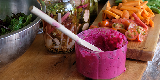 Vibrant pink dip and assorted vegetables displayed on an outdoor wooden table