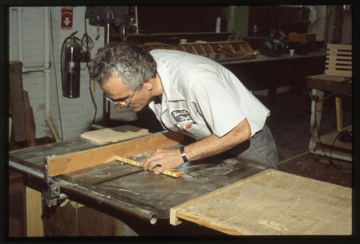 A man takes a measurement on a table saw.