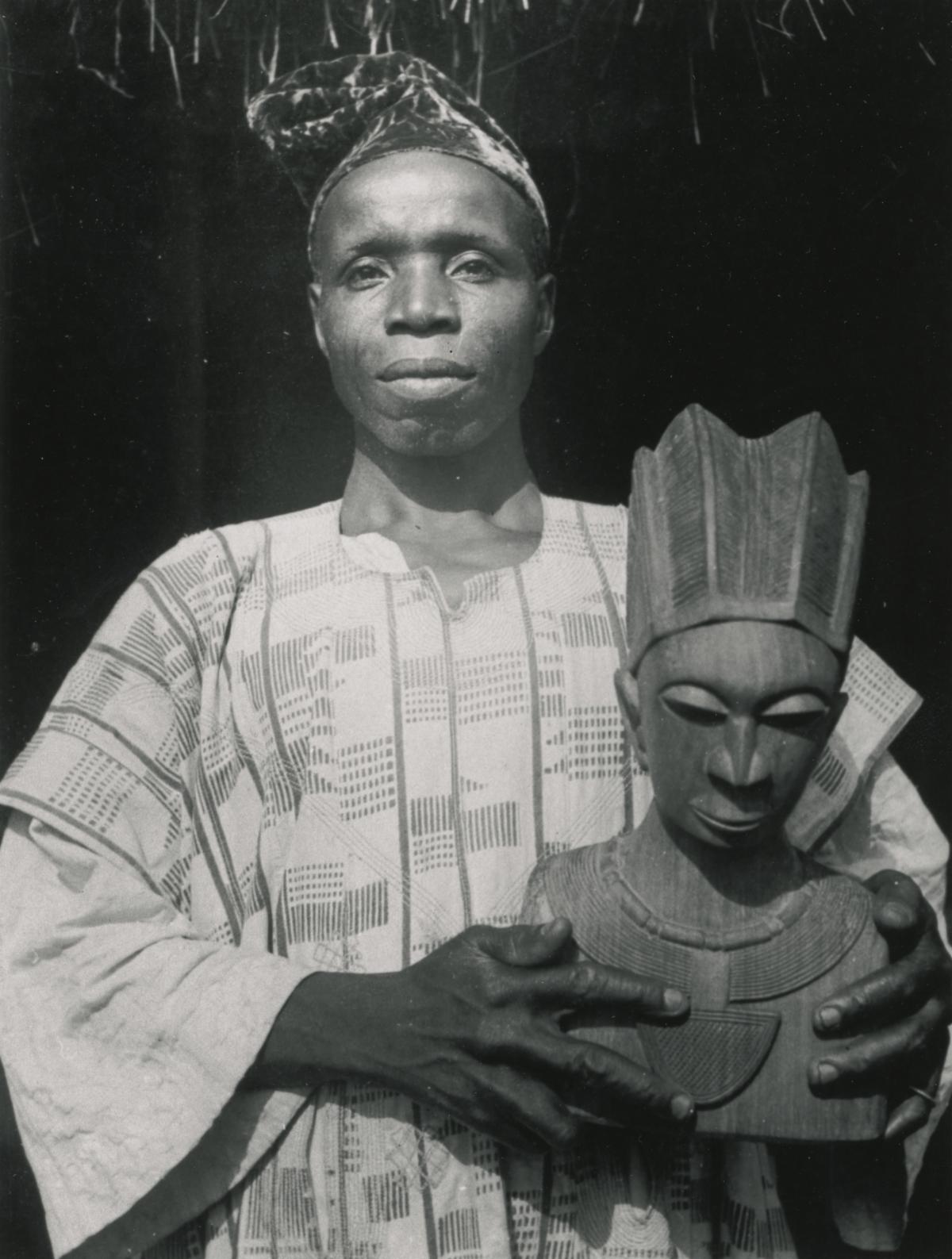 The artist Bámigbóyè Holding a Portrait Bust of a Woman