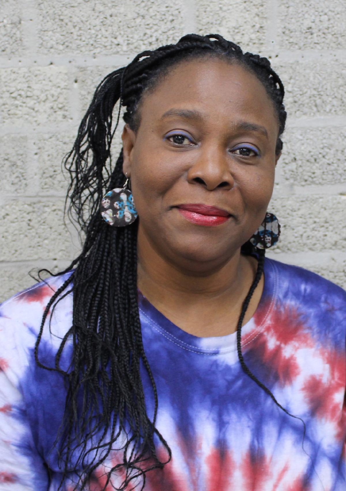 A woman wearing braids and a tie dyed shirt