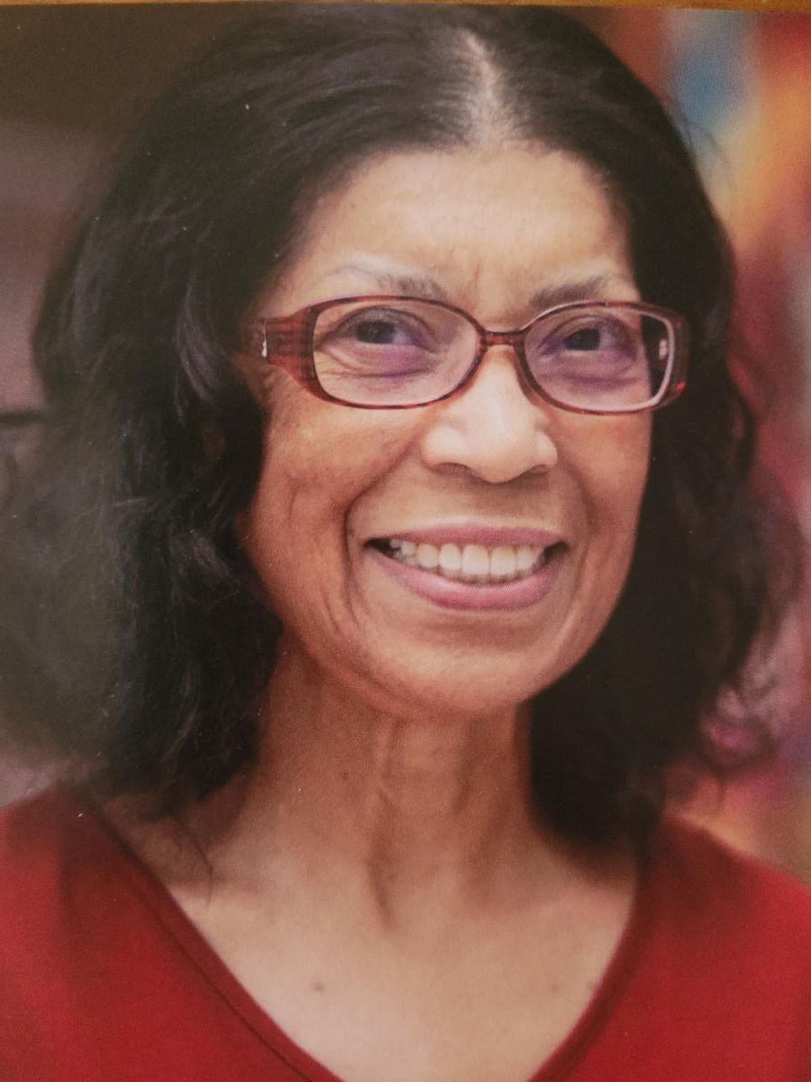 A smiling woman with wavy dark hair and glasses
