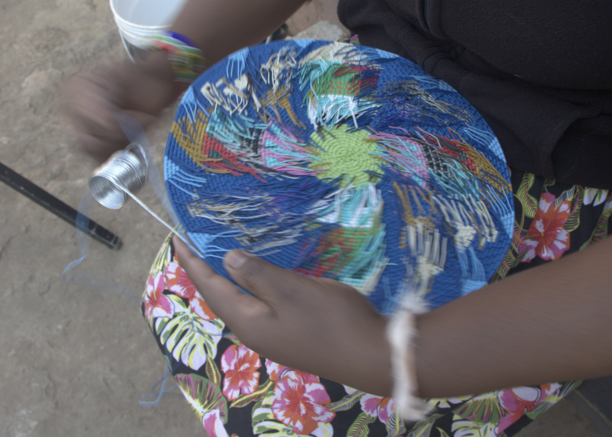 Woman's hands weaving blue telephone wire plate