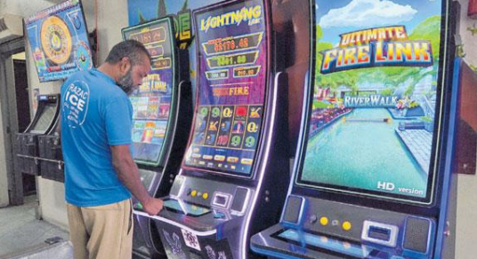 Flashback: Ramesh Ramsaran tries his luck on one of the many electronic gambling machines at Universal Bar in St James in July. PHOTO BY ROGER JACOB
