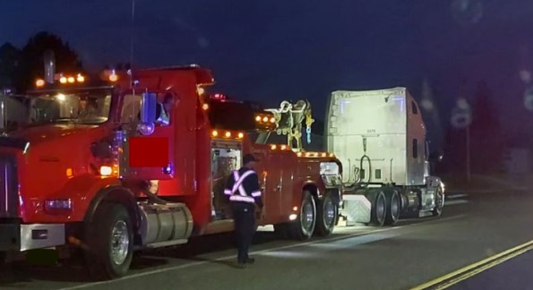 A commercial motor vehicle is pulled over on the side of the highway at night