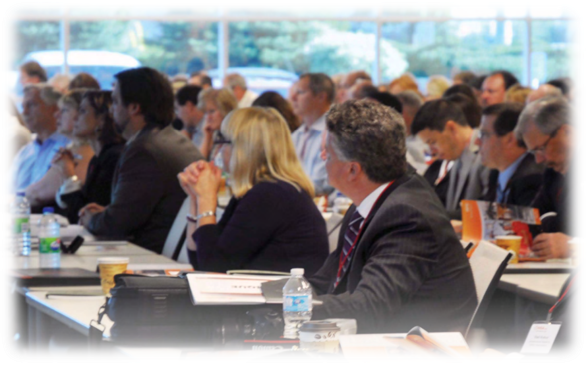 Attendees sit at an event table and listen to a speaker