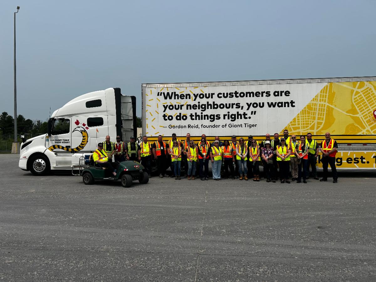 Attendees at the FSC Eastern Chapter meeting stand in front of a Giant Tiger vehicle.