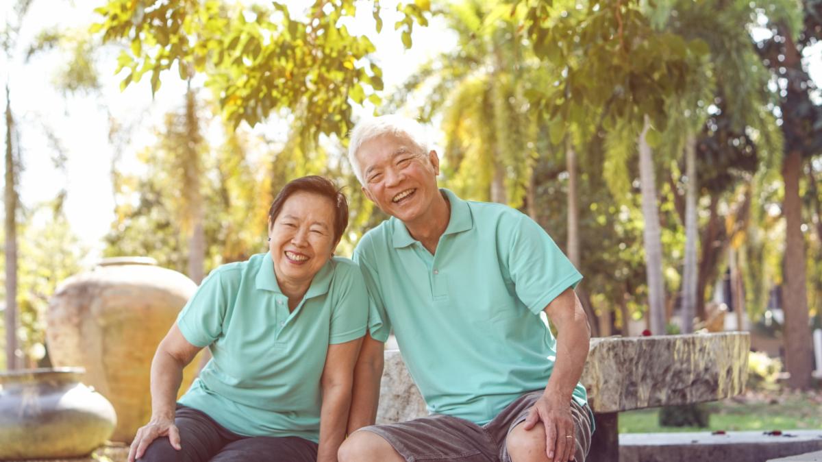 Two seniors sit down outdoors in hot summer weather