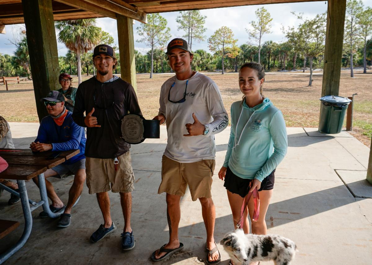 The heavyweight champions hold their heavyweight belt. Two men and a woman holding the leash of a dog