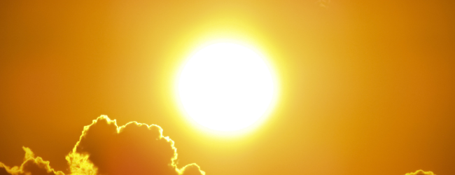 A yellow sky with a cloud and the blazing sun