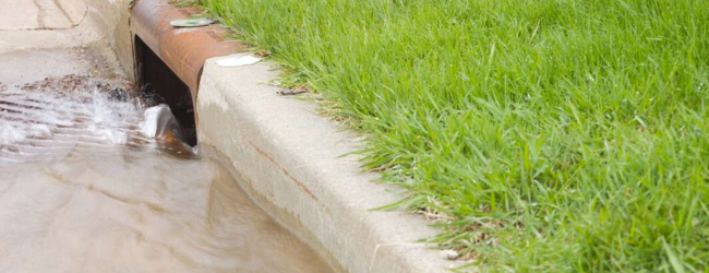 A storm drain with water gushing into it