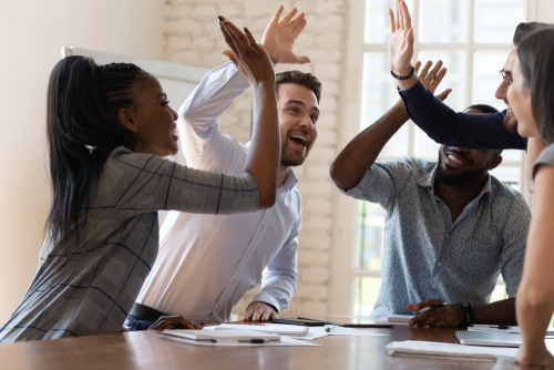 Multiracial euphoric business team people give high five at office table_ happy excited diverse work group engaged in teambuilding celebrate corporate success win partnership power teamwork concept