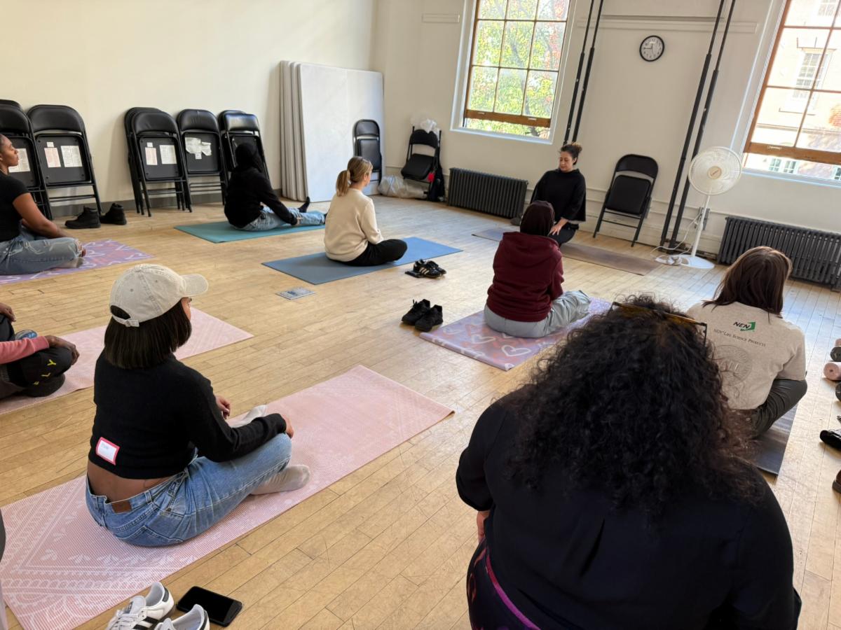 People are sitting on yoga mats in a well lit room.