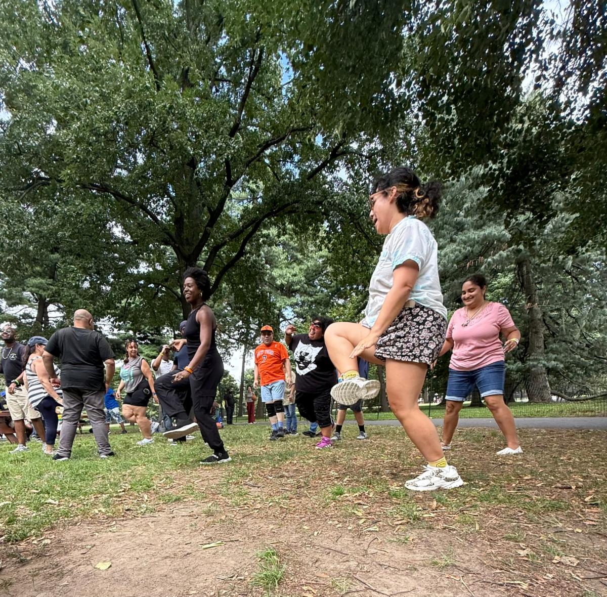 Looking up from a worm's eye view, a group of people dance in the park. 