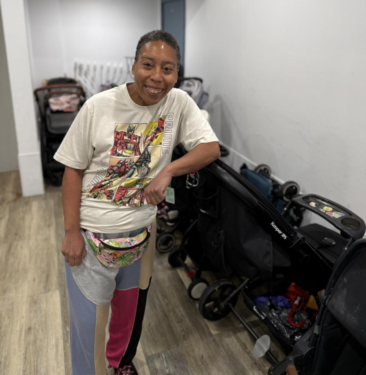 Alvena is leaning up against a stroller in a room inside the Y. 