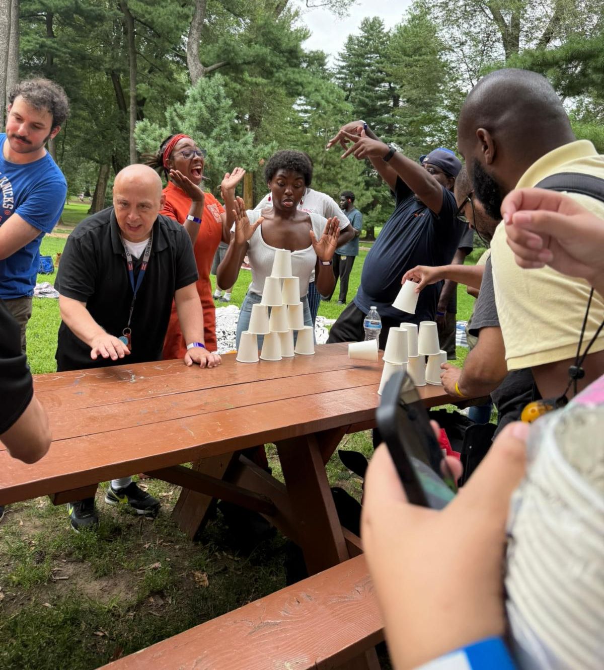 In a cup stacking game, a group celebrates their success with cheering and laughter. 