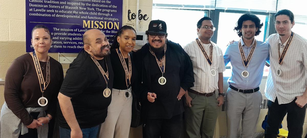 A line of people standing smiling and each person is wearing a medal around their neck. 