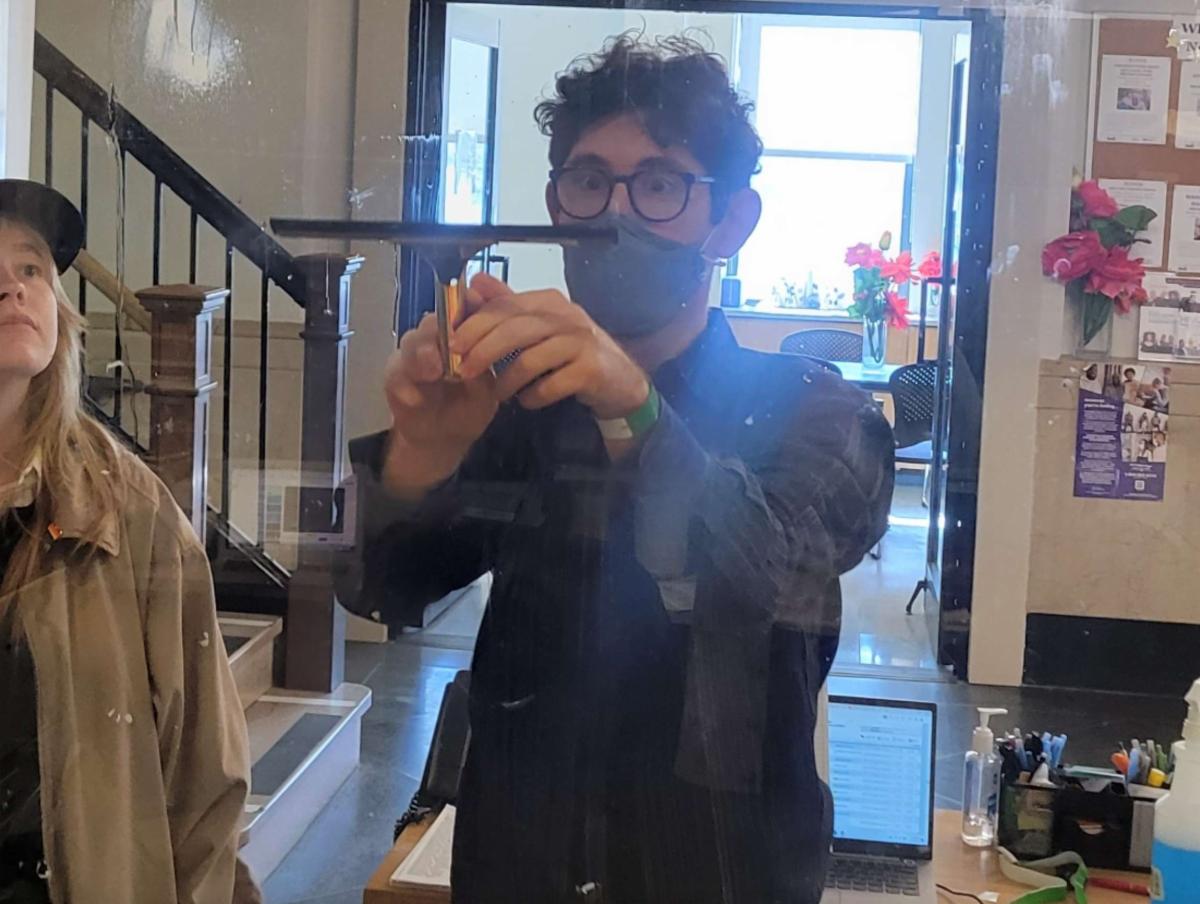 Jake is using a squeegee on a mirror. 