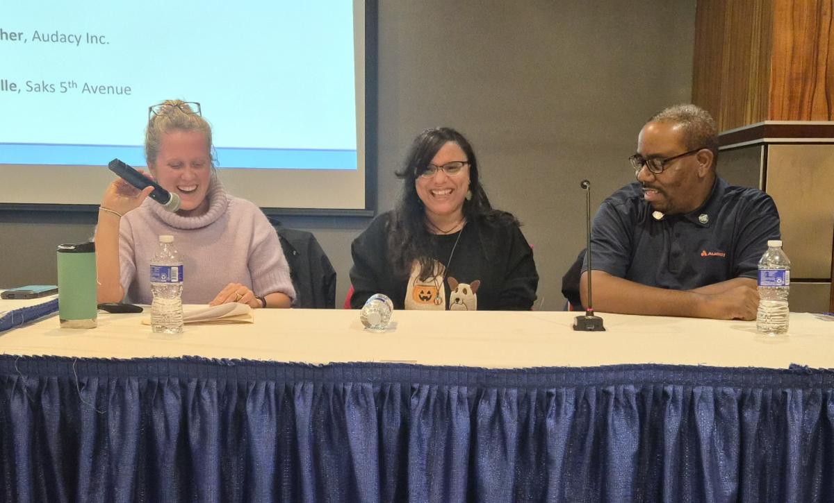 Aimee Jaide and Will sit at a table with Aimee on the mic. 