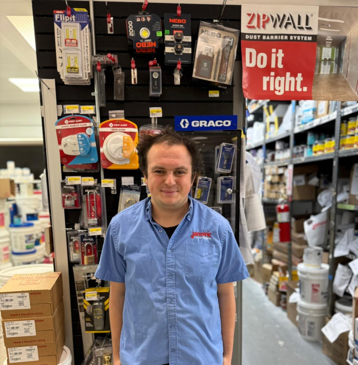 Leo wears a blue company shirt and stands in front of an aisle of merchandise. Above his shoulder is a sign that reads "Do it right." 