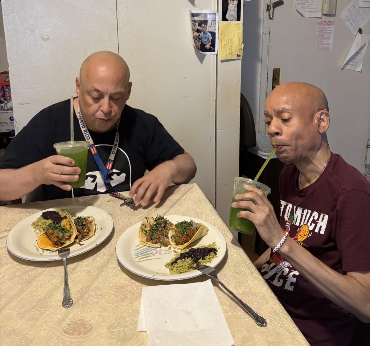Cornell and Steven sit at a table with delicious looking drinks and tacos.