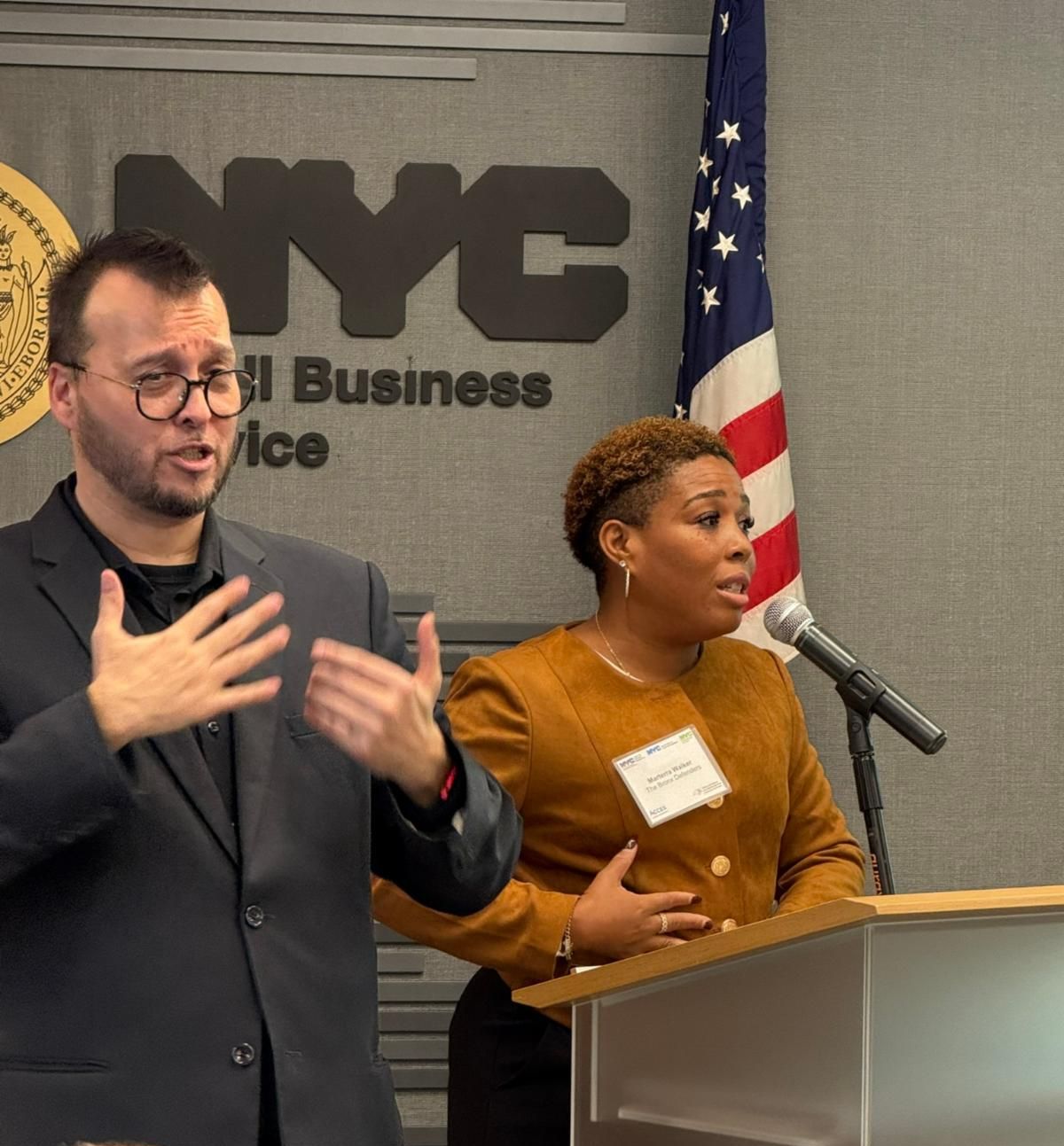 Marterra Walker is standing at a podium with an American flag behind her and a ESL translator next to her