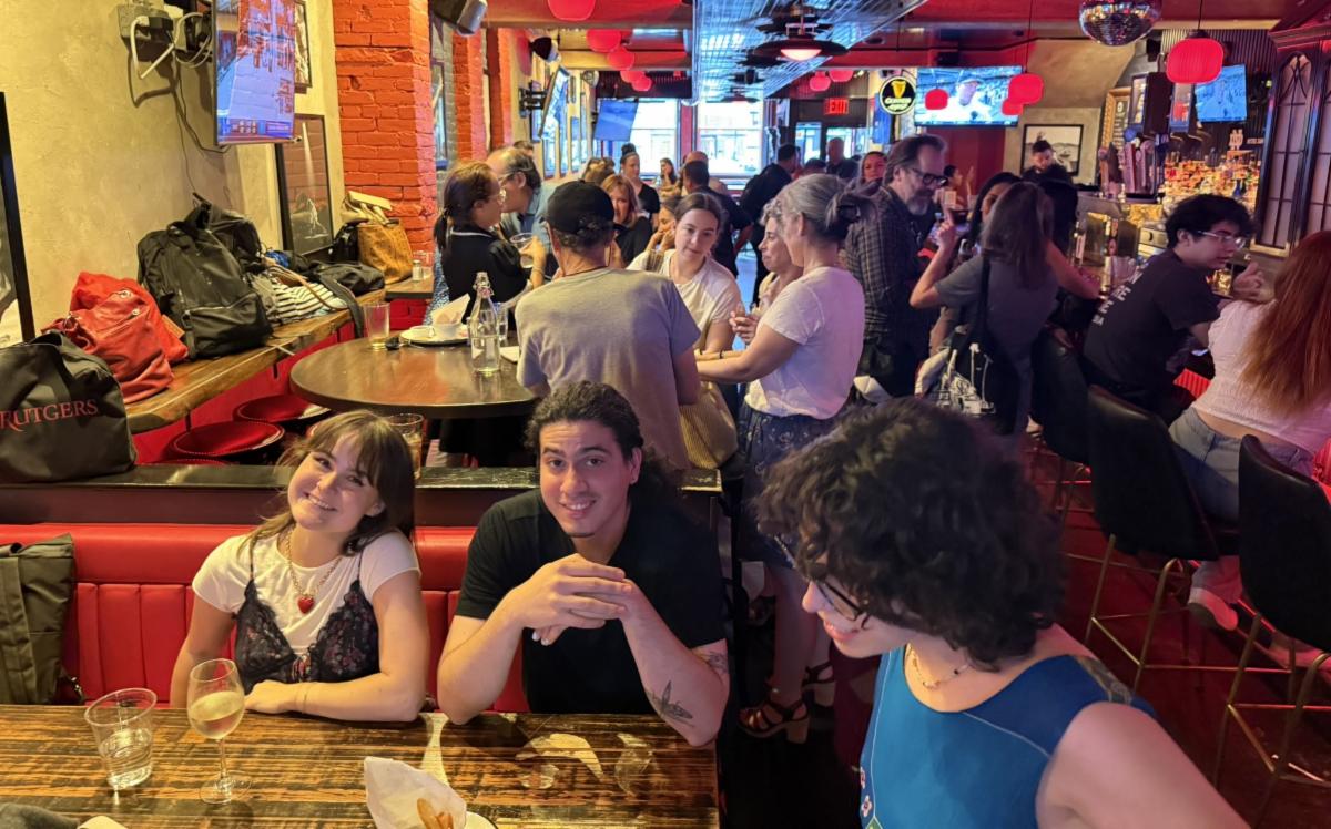 People are smiling and laughing in a crowded bar. 
