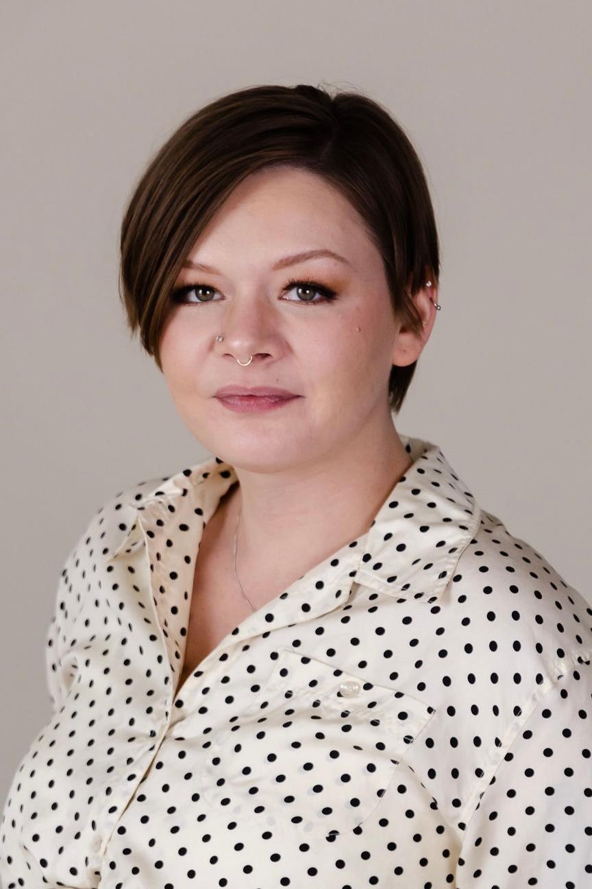 Rachel is wearing a white shirt with black polka dots and she has short brown hair.