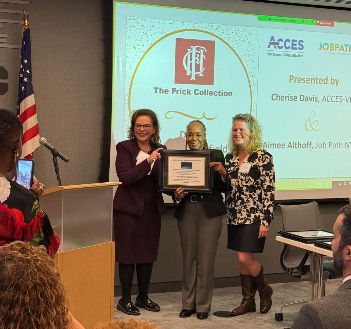 Award honorees stand in front of a screen with the frick logo.