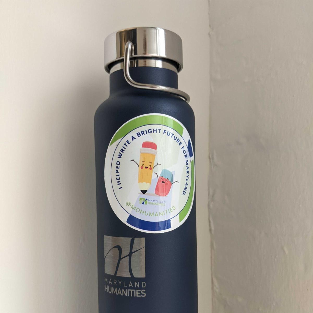 Image of a water bottle with a sticker that quote says I helped write a bright future for Maryland unquote. The sticker has a personified pencil and a personified eraser that both look happy. We see the words Maryland Humanities and @mdhumanities