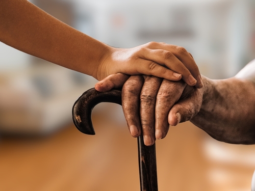An elderly person holding a cane with a younger hand offering support_ symbolizing assistance and stability for senior citizens.