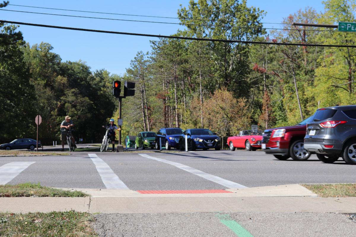two bicyclists waiting to cross a busy street