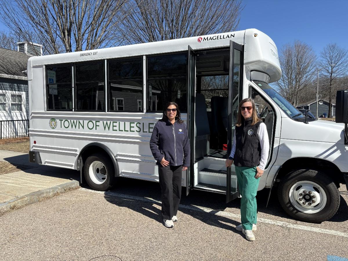 Picture of Town of Wellesley white mini bus with two women, Wanda Alvarez and Maura Renzella, standing in front of the mini bus