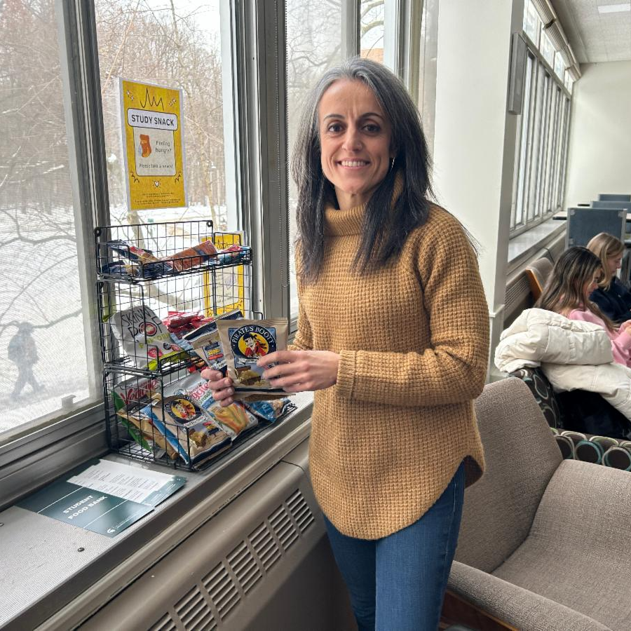 Advisor Carmen Ruiz-Sanchez poses by one of the community pantry locations from the fall. The shelf is loaded with snacks free to Briggsies who have need