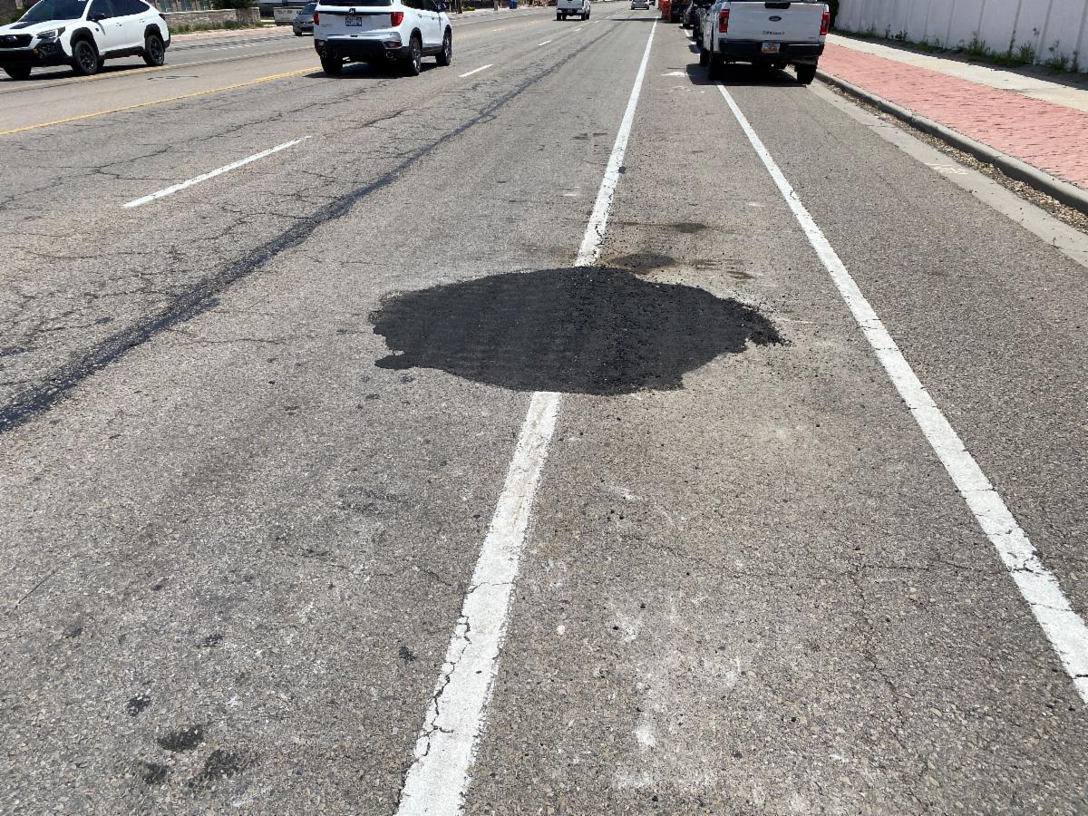This is a utility lid that has been lowered and covered with temporary asphalt prior to the milling process.