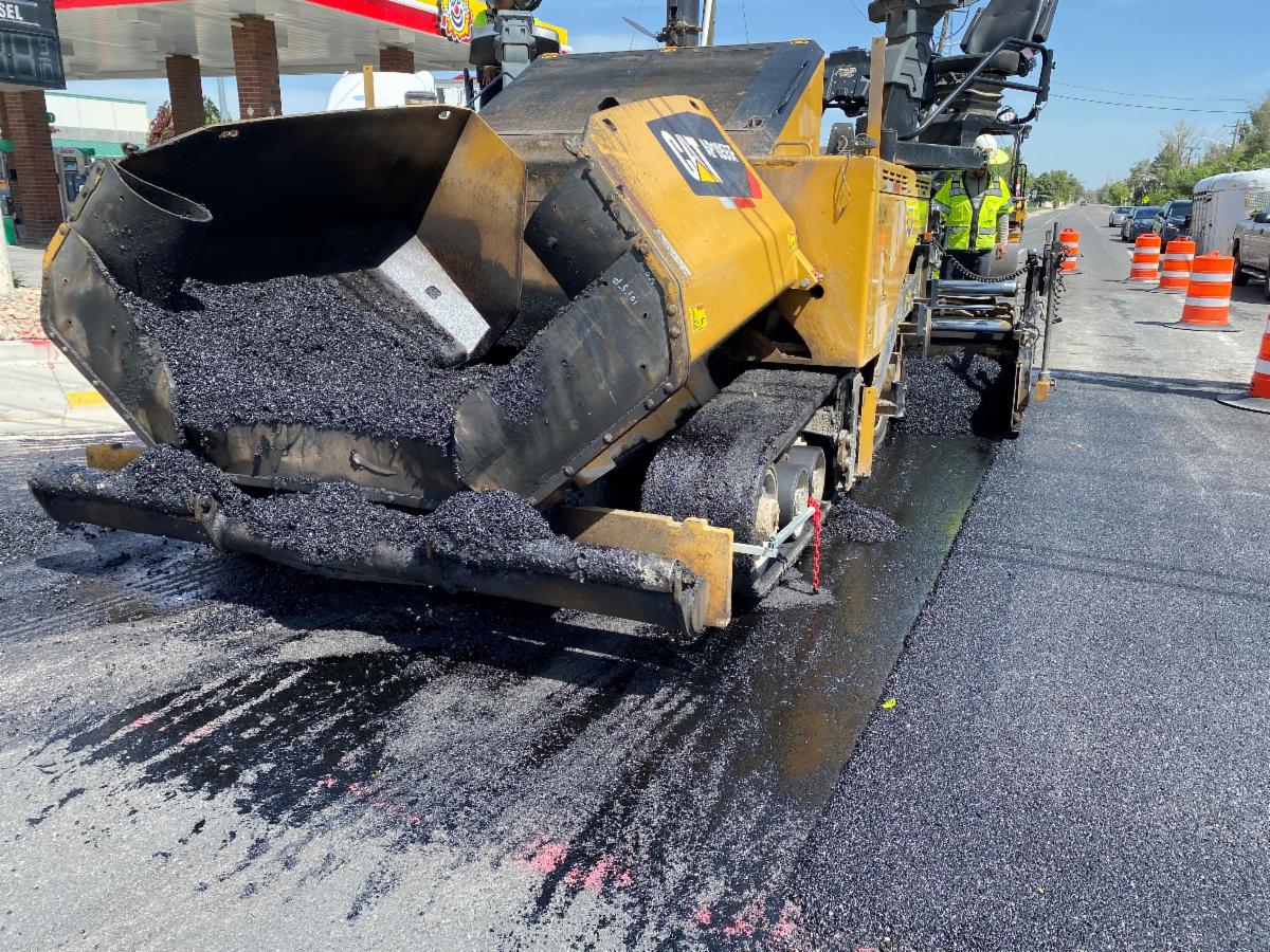 Crews placing the top layer of asphalt on 9000 South. This top layer provides a smooth ride and removes water from the road to improve traction. 