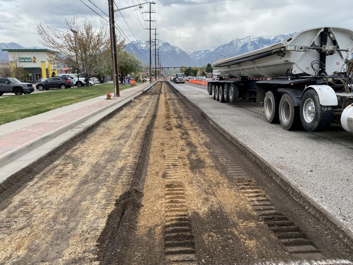 Pictures of equipment removing the asphalt (milling) and shooting the debris into a dump truck leaving the bare road base below. Crews will add new material to the base prior to placing 7 inches of asphalt.