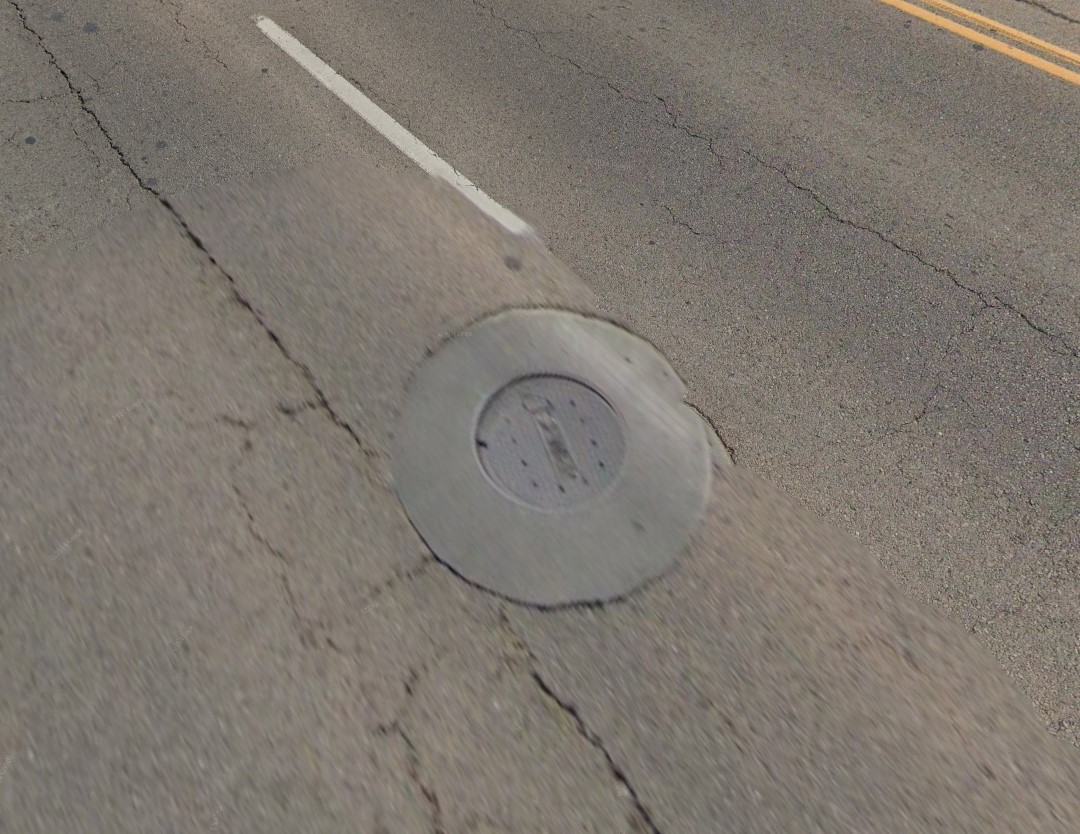 This is a utility lid that has not been lowered. Utility lids are lowered prior to the milling process to prevent the equipment from being damaged. 