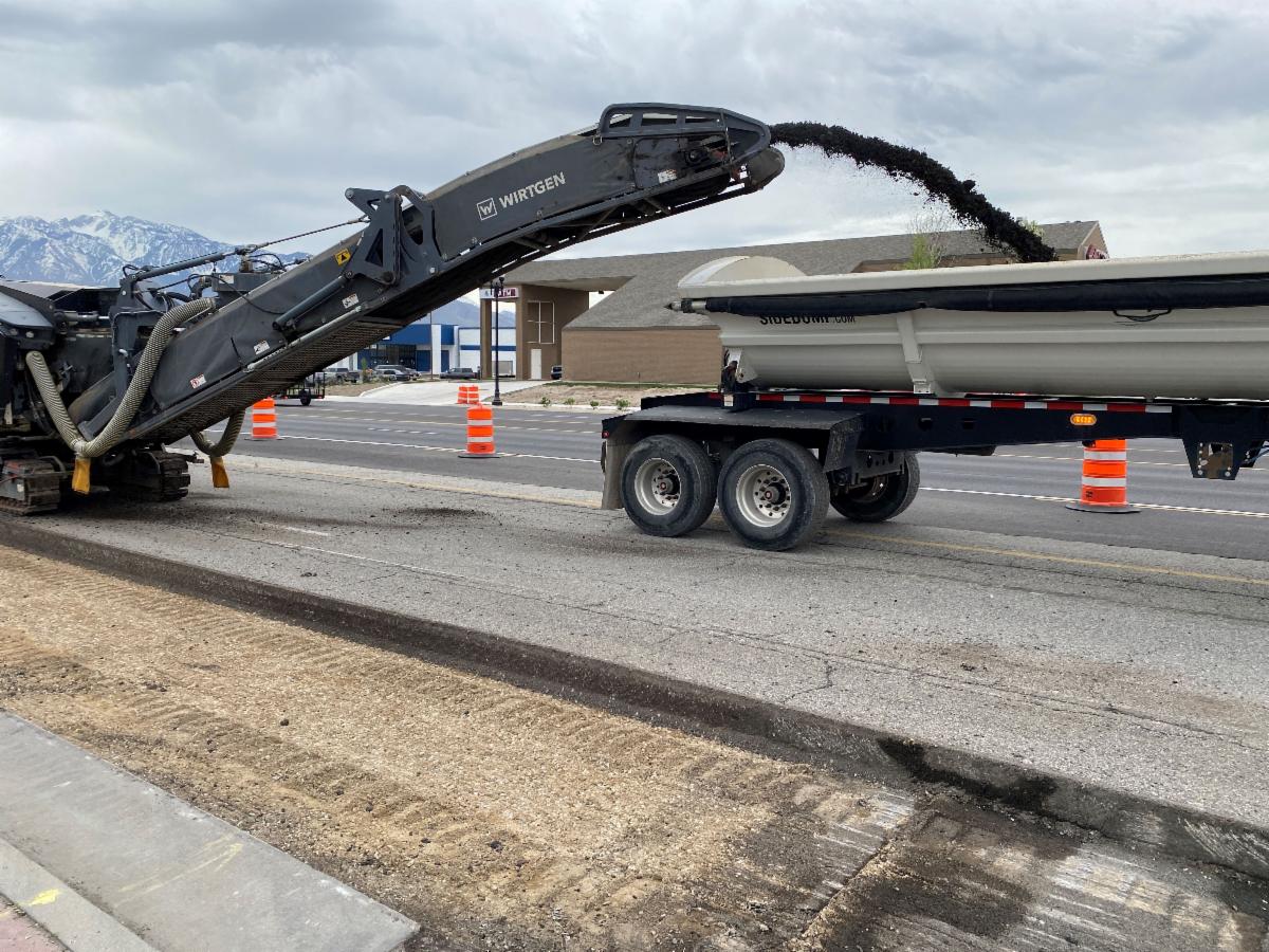 Pictures of equipment removing the asphalt (milling) and shooting the debris into a dump truck leaving the bare road base below. Crews will add new material to the base prior to placing 7 inches of asphalt.