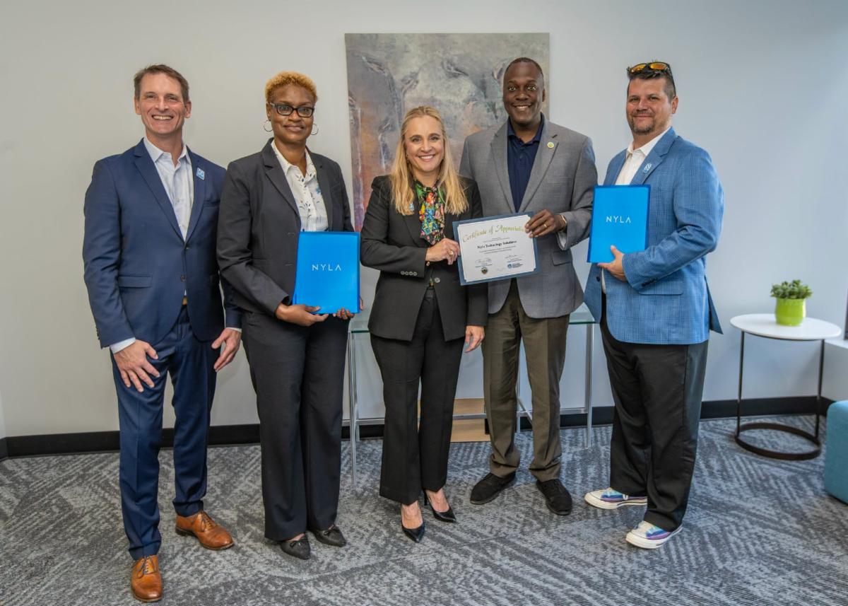 A photo of Calvin Ball and Jennifer Jones posing with the owners of Nyla Technology Solutions.